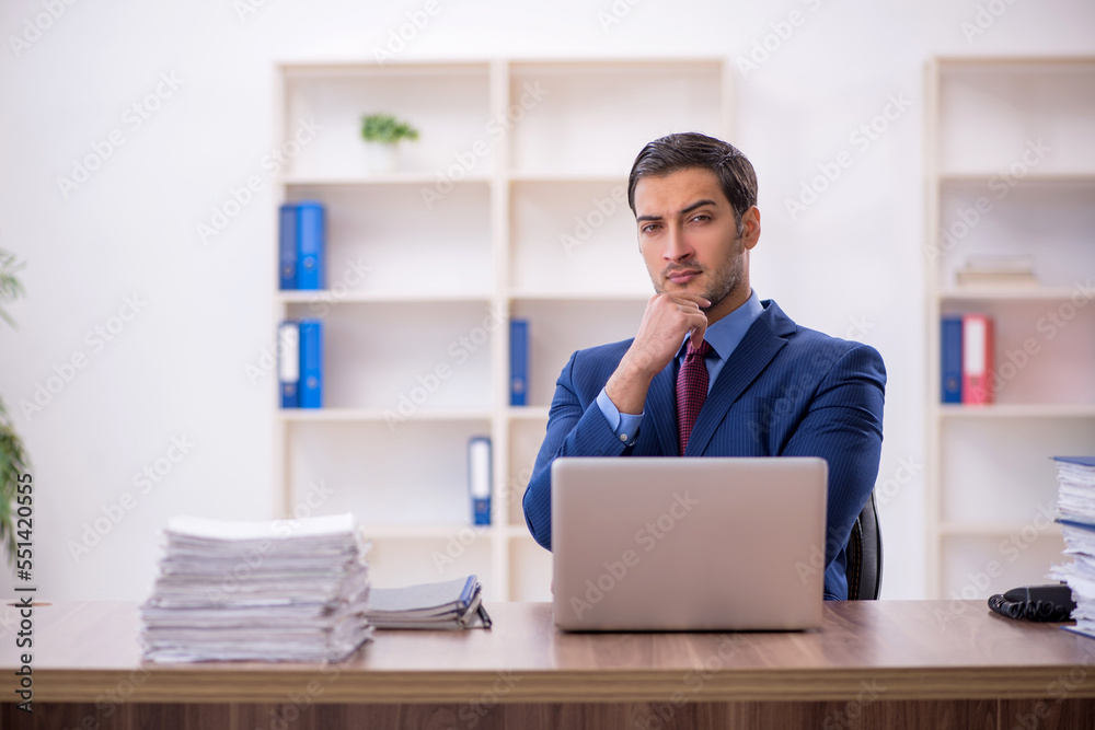 Young male employee and too much work in the office Young male employee and too much work in the office