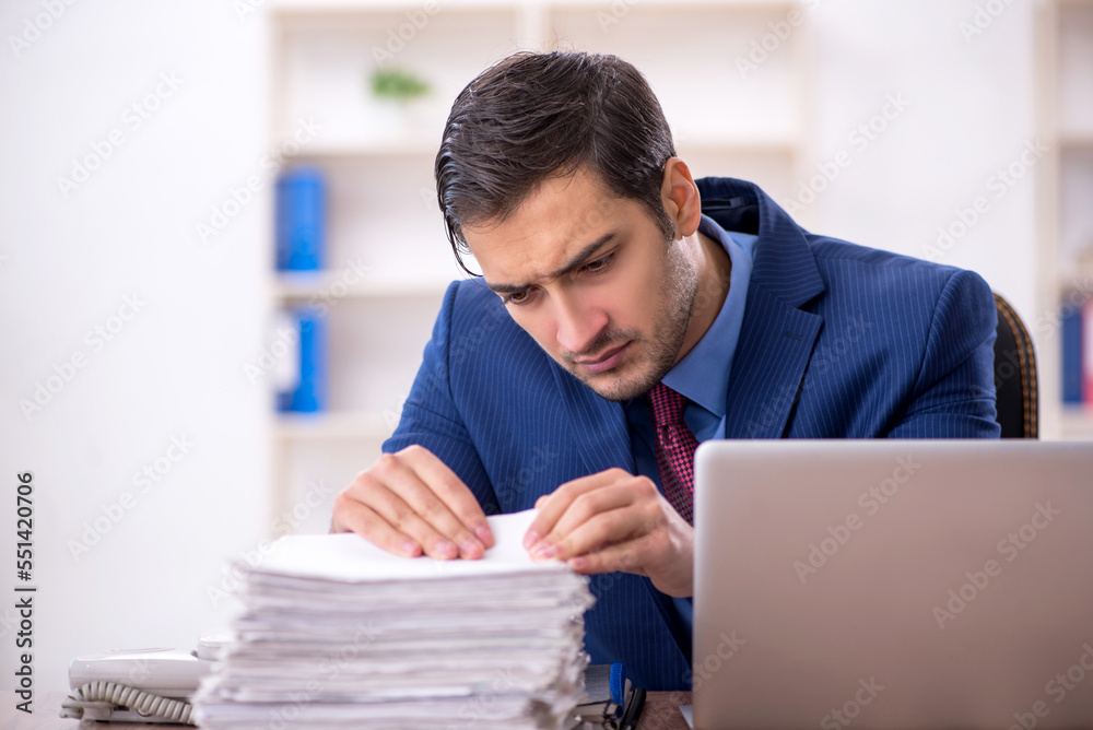 Young male employee and too much work in the office Young male employee and too much work in the office