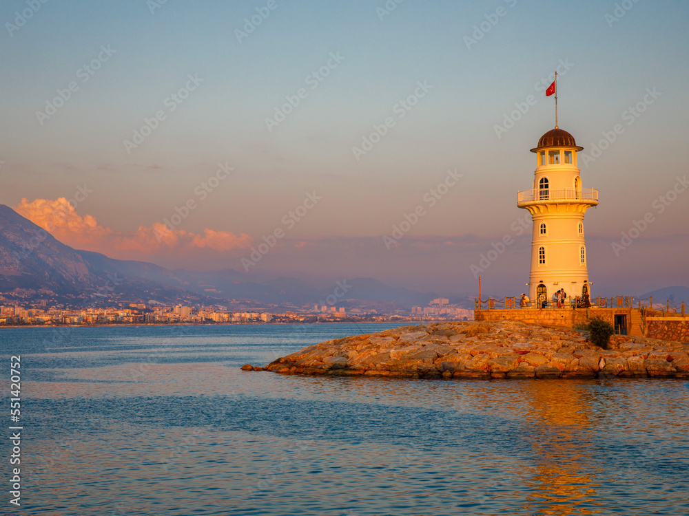 Old Alanya Deniz Feneri lighthouse in Alanya port at sunset. Popular tourist destination in Turkey. Summer travel vacation. View from embankment to beacon.