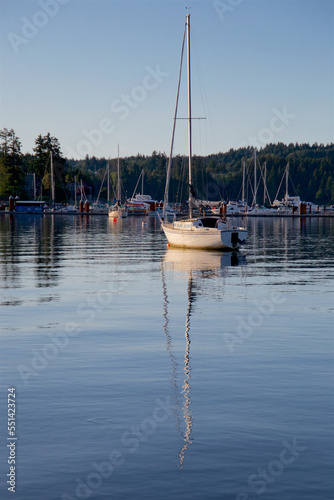 Sailboat at anchor in the habor in front of the marina at sunset on a summer day. © Alain Bechard