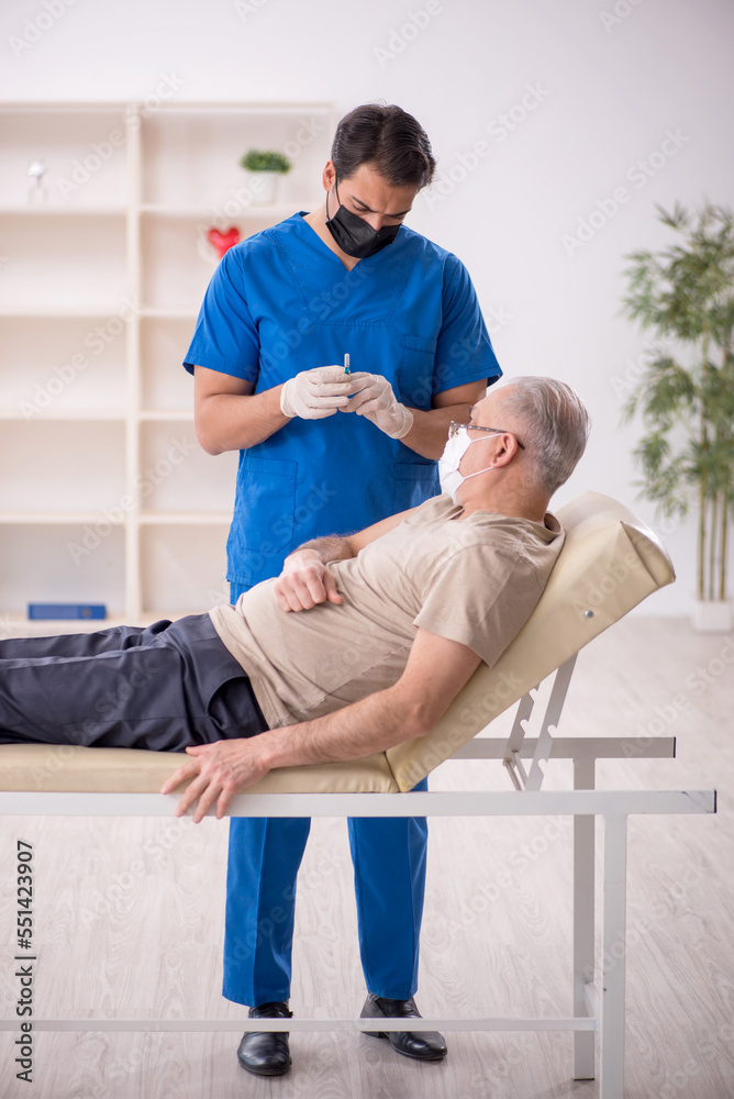 Obraz premium Old male patient visiting young male doctor in vaccination conce