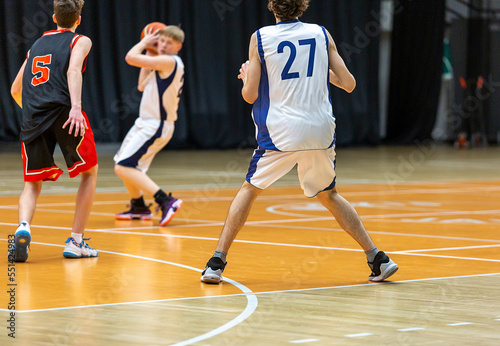 Boys teenagers playing basketball. Group of players in action with a ball. Sports activity, lifestyle.