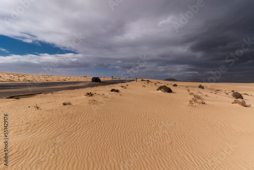 Corralejo highway with passing car and some dark blue clouds in distance near Atlantic ocean  Canary Islands 