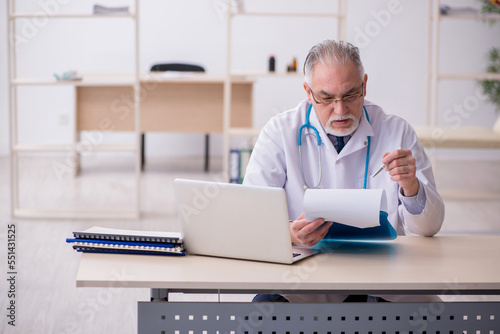 Old male doctor working in the clinic