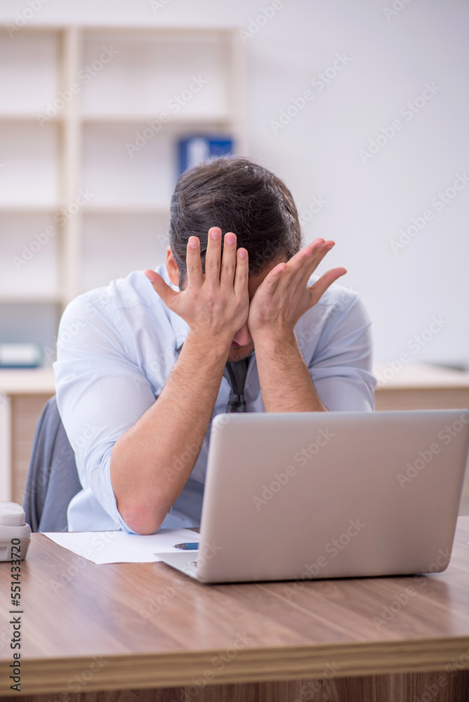 Young male employee unhappy with excessive work in the office Young male employee unhappy with excessive work in the office