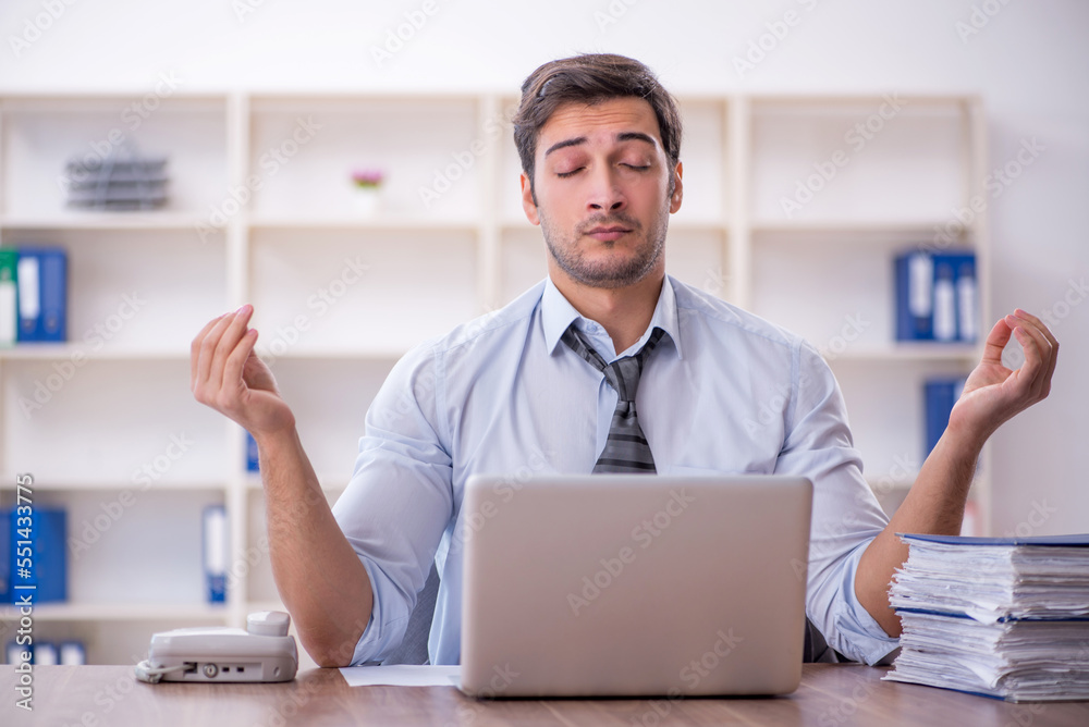Young male employee unhappy with excessive work in the office Young male employee unhappy with excessive work in the office