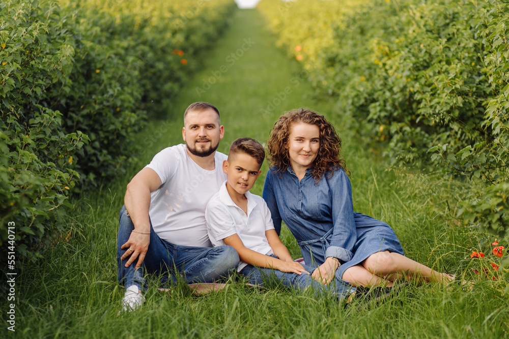 Young family looking at the camera while walking in the garden Young family looking at the camera while walking in the garden