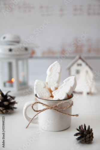 New Year and Christmas atmosphere, December 25 on the calendar. Cup with drink, pine cones, lantern, candle, fire, Christmas fire and marshmallow, tree house behind