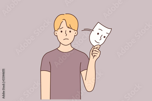 Unhappy man take off smiling mask 