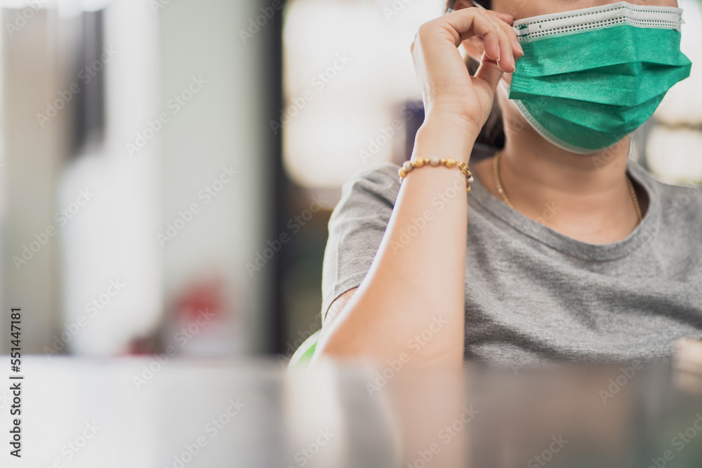 Close-up of young Asian woman wearing a green face mask to prevent respiratory infections. Respiratory disease prevention concept