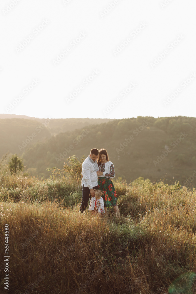 Beautiful family with kid in traditional ethnic dress in a countryside, park
