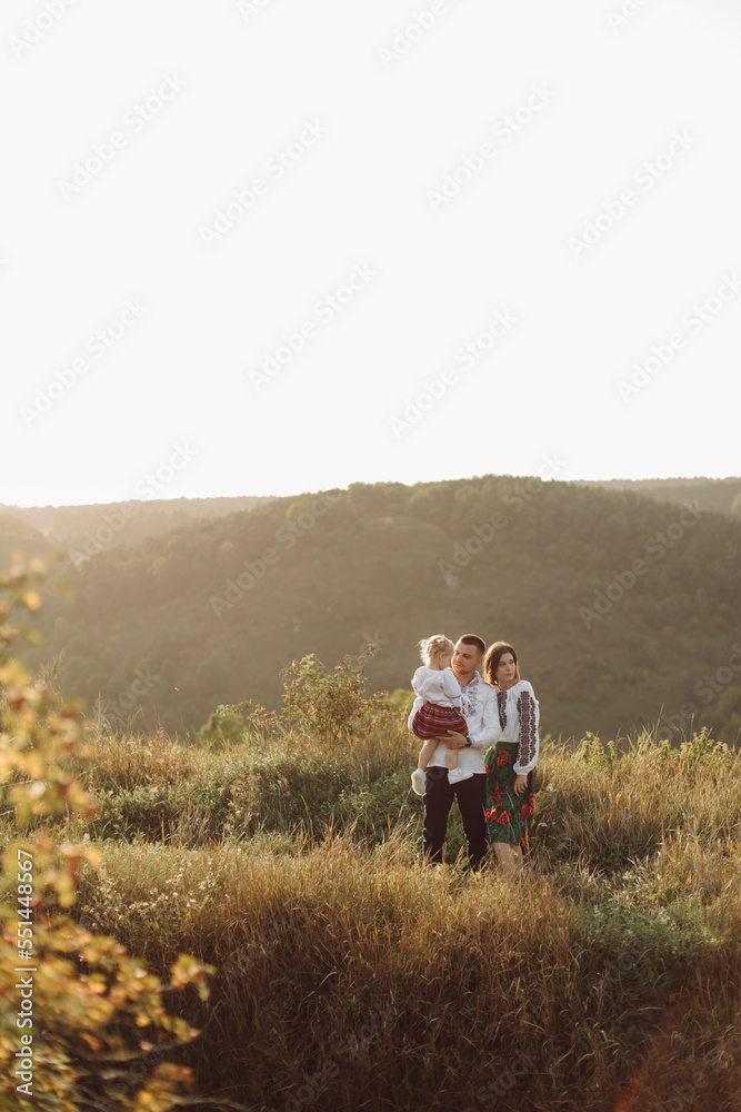 Beautiful family with kid in traditional ethnic dress in a countryside, park Beautiful family with kid in traditional ethnic dress in a countryside, park