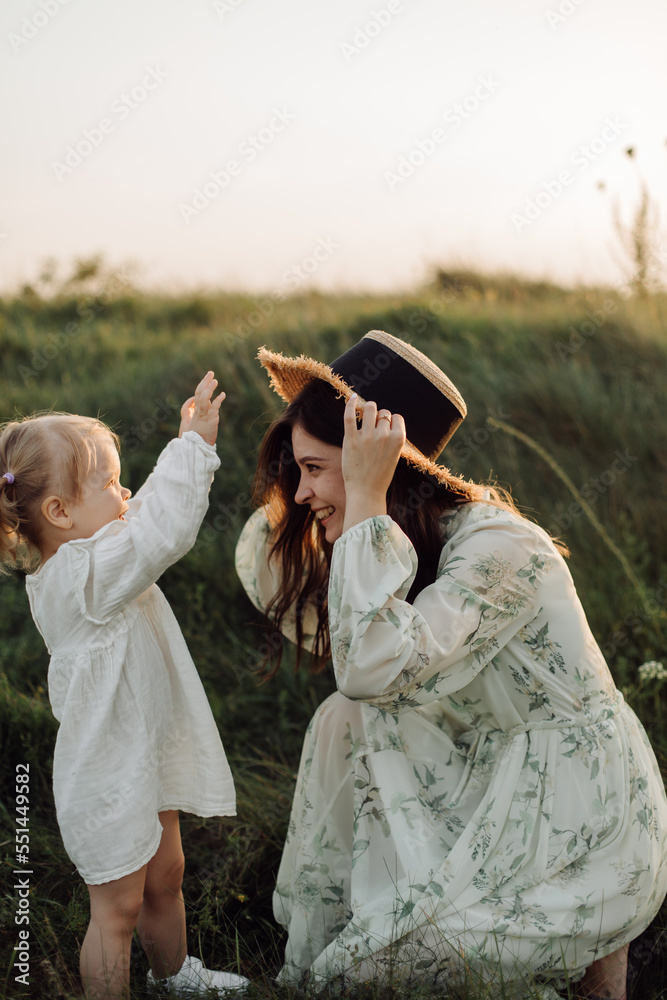 Beautiful caucasian family of father, mother and little daughter posing on camera on background of green field Beautiful caucasian family of father, mother and little daughter posing on camera on background of green field
