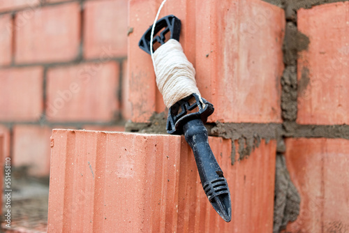 Rope plumb for even brickwork. Compliance with the correct laying of walls and corners of ceramic bricks. Bricklayer's tool.