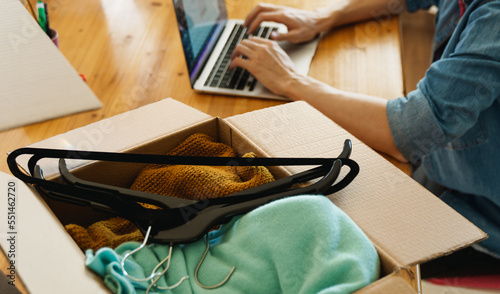 Box parcel with clothes inside on desk, reselling pre owned clothes online concept.