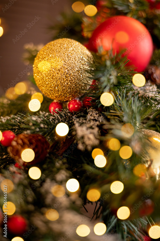 Close-up of red and gold decorations on a Christmas tree. New Year's brown background with lights