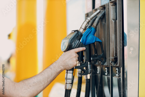 Man holding filling gun in his hand at gas station.