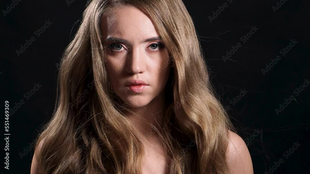 Luxurious golden curls, portrait of a young beautiful woman with beautiful hair, Portrait on a black background. Hair fluttering in the wind Luxurious golden curls, portrait of a young beautiful woman with beautiful hair, Portrait on a black background. Hair fluttering in the wind