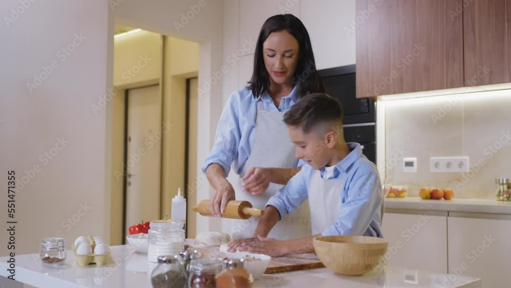 Cheerful mom and son kneading dough in kitchen, family cooking pastry together Cheerful mom and son kneading dough in kitchen, family cooking pastry together