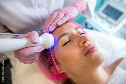 beautiful woman receives ultrasonic skin cleaning and facial treatment in a beauty salon