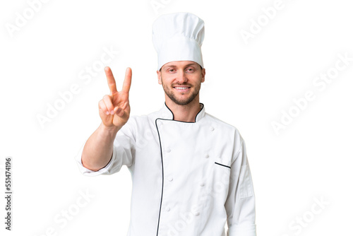 Young caucasian chef over isolated chroma key background smiling and showing victory sign