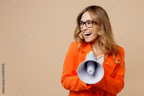 Obraz na plátně Young employee business woman corporate lawyer wear classic formal orange suit glasses work in office hold scream megaphone announces discounts Hurry up look aside isolated on plain beige background