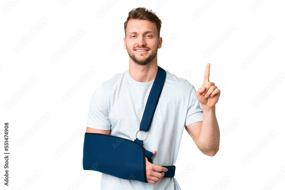 Young caucasian man with broken arm and wearing a sling over isolated chroma key background showing and lifting a finger in sign of the best Young caucasian man with broken arm and wearing a sling over isolated chroma key background showing and lifting a finger in sign of the best