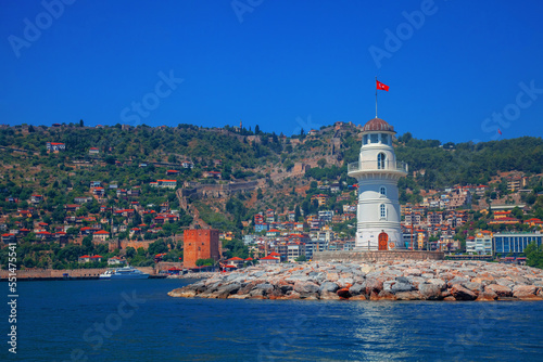 Landscape of lighthouse in the port of Alanya. White lighthouse in seaport of Alanya with concrete path and stones. Copy space for text.