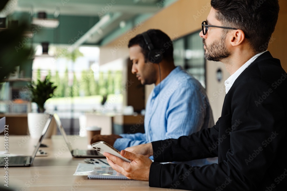 Two multiethnic businessmen working together in office Two multiethnic businessmen working together in office