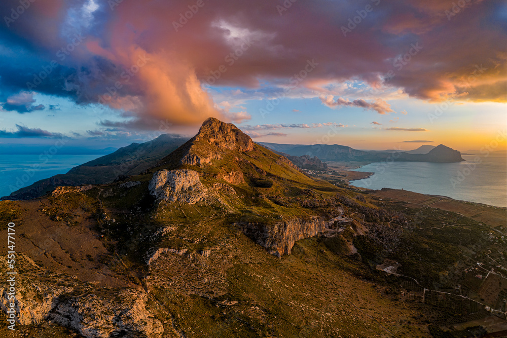 Obraz premium Photo from the drone on the panorama of the Mediterranean coast. View of Monte Monaco and Monte Cofano in the distance. The colorful sky covers the top of the mountain. golden hour. Sicily. Italy