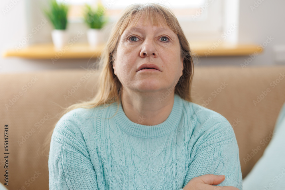 Indoor portrait of happy elderly woman hugging herself, giving support, showing self-respect and love, sitting on couch with closed eyes in urquoise sweater. Human emotions, body language Indoor portrait of happy elderly woman hugging herself, giving support, showing self-respect and love, sitting on couch with closed eyes in urquoise sweater. Human emotions, body language