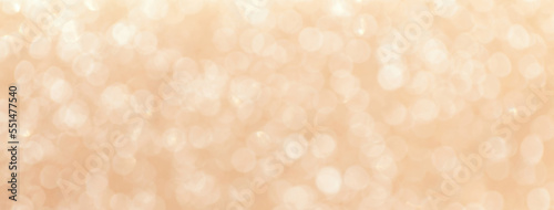 Blurred light beige sparkling background from small sequins, macro. Brown defocused backdrop