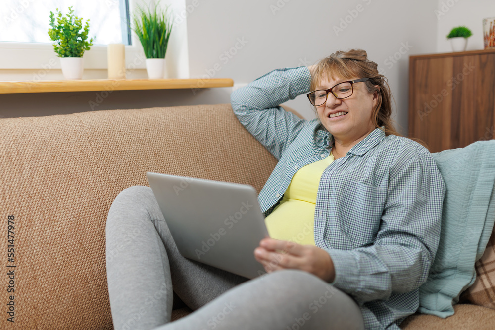 Technology, old age and people concept - happy senior woman in glasses with laptop computer and glass of wine at home Technology, old age and people concept - happy senior woman in glasses with laptop computer and glass of wine at home