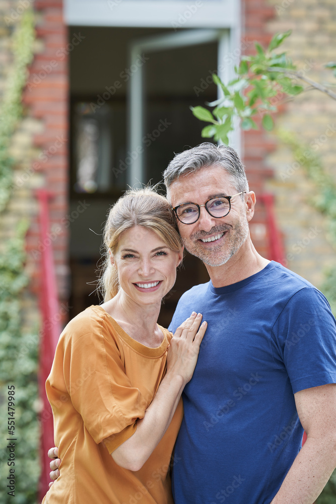 Smiling mature man embracing woman in front of house Smiling mature man embracing woman in front of house