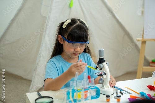 education, science and children concept - girl in goggles studying test tube with chemical at home laboratory