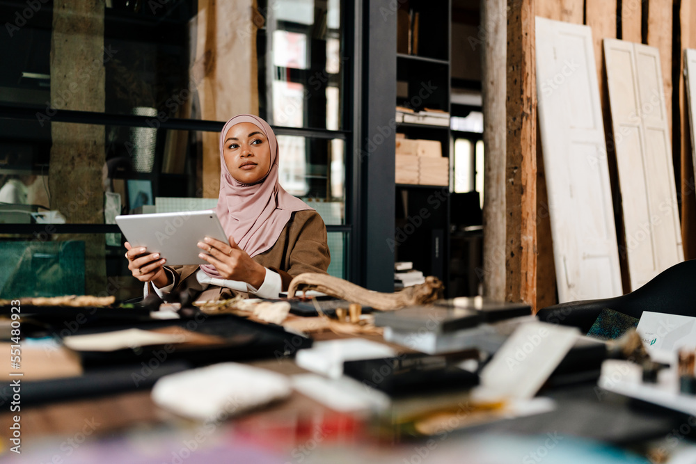 Arabian woman designer working on tablet at workshop