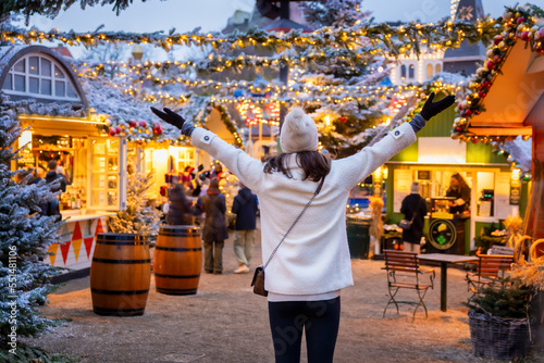 Obraz na płótnie A happy tourist woman stands on a christmas market in Copenhagen, Denmark, with illuminated decorations during winter dusk w salonie