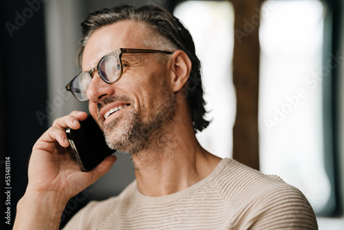 Closeup of middle-aged man smiling while talking on cellphone indoors