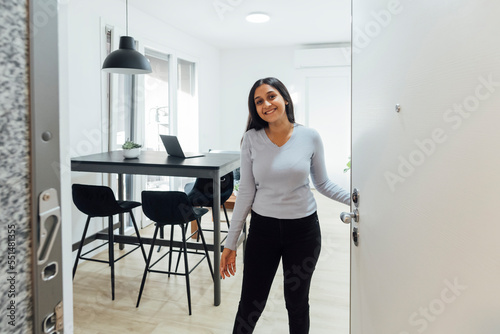 Smiling young woman opening door