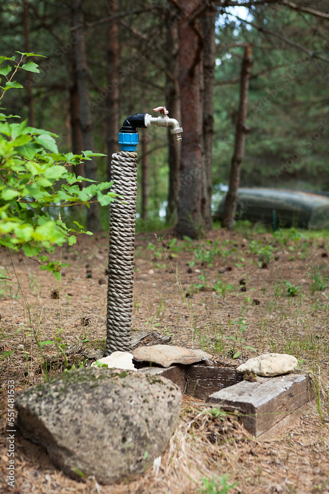 Naklejka premium Modern faucet in the backyard of the wooden houses to connect the hose and watering the plants