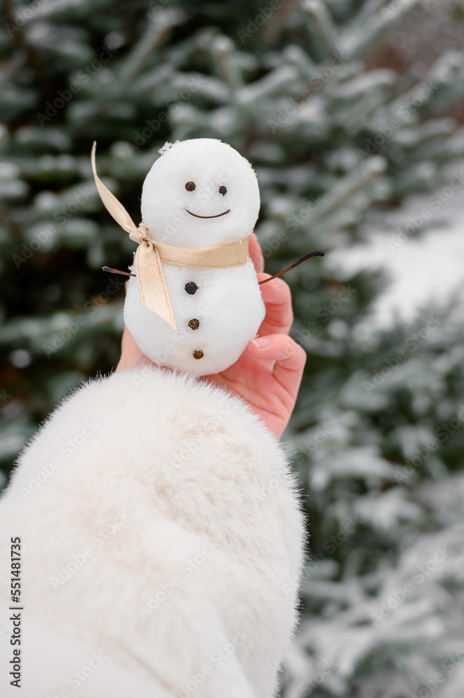 A small snowman in female hands. Cute snowman. winter photo