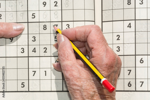 Old woman's hand with pencil doing a sudoku. 
