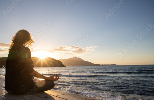 woman meditating by the sea at sunset © Melinda Nagy