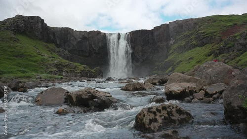 View of Gufufoss waterfall flowing through rocks with tourist travelling in summer at Seydisfjordur, Iceland photo