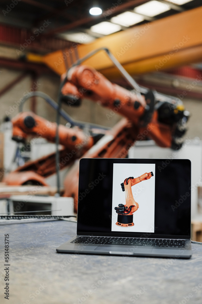 Laptop with robotic arm picture at desk in industry Laptop with robotic arm picture at desk in industry