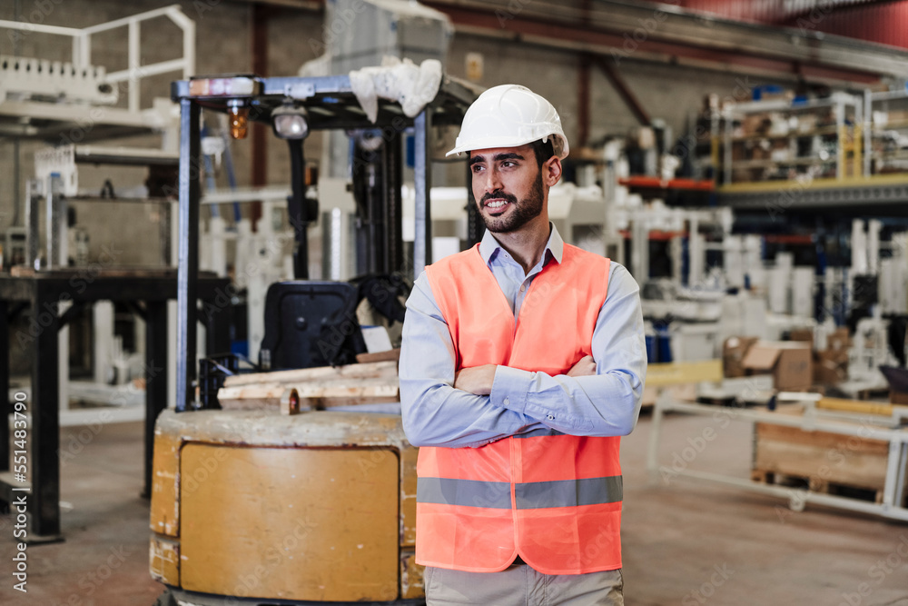 Smiling engineer wearing hardhat standing in industry Smiling engineer wearing hardhat standing in industry