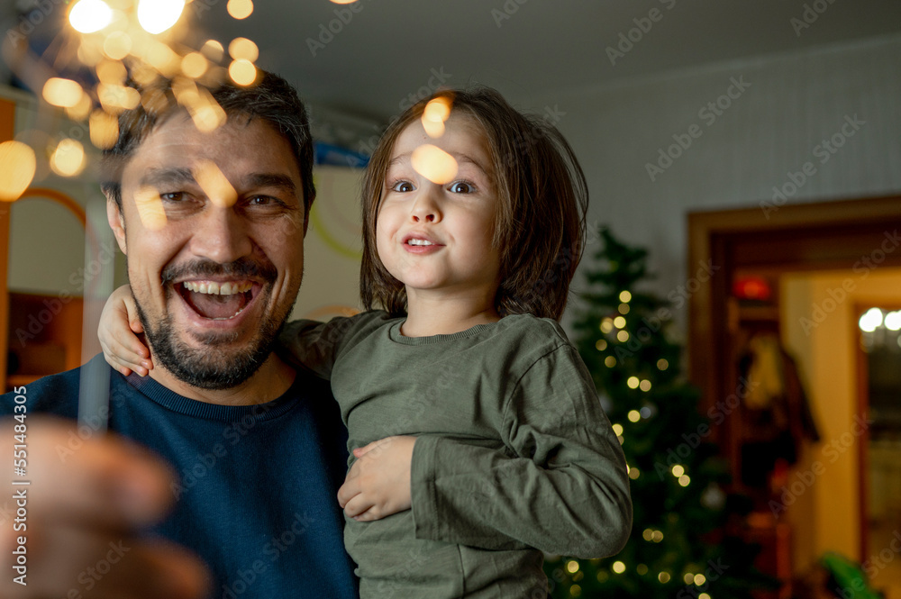 Happy father with son holding sparkler at home Happy father with son holding sparkler at home