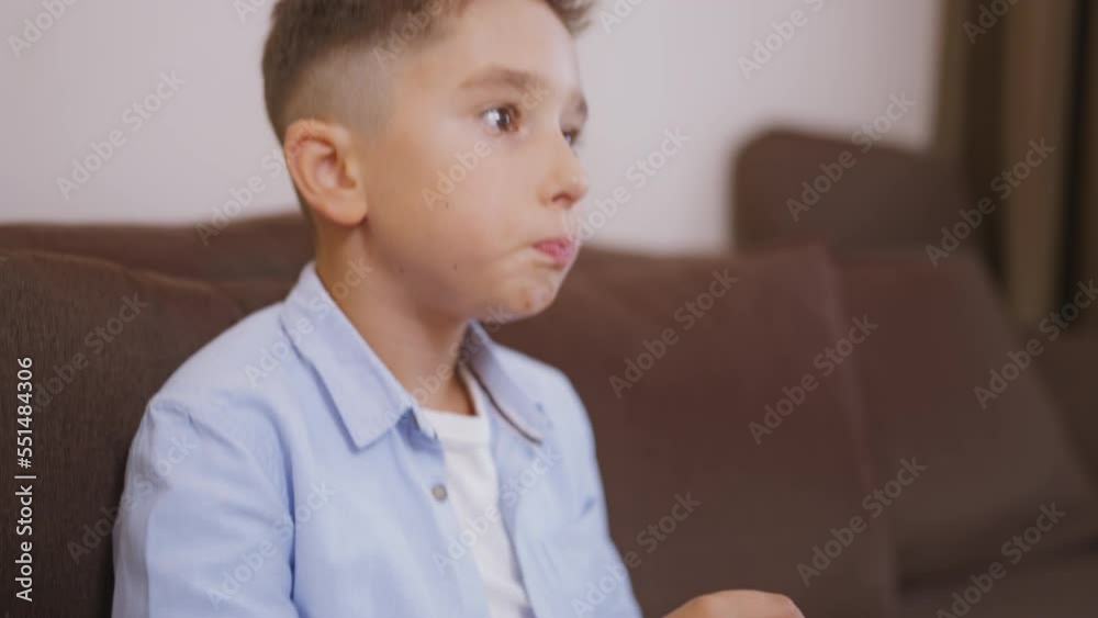 Excited little boy sitting on couch watching tv, eating popcorn, unhealthy snack Excited little boy sitting on couch watching tv, eating popcorn, unhealthy snack