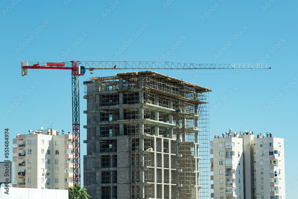 Construction crane and building under construction among other residential in the city. Construction crane and building under construction among other residential in the city.