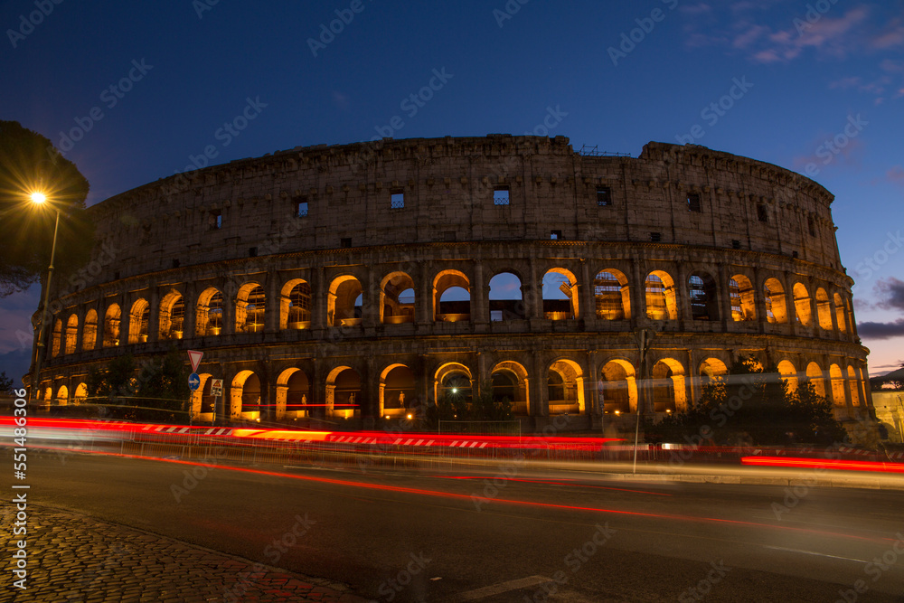 The Colosseum at sunset. It is an oval amphitheatre in the centre of the city of Rome, Italy. It's called also Flavian Amphitheatre. Car traffic passes by.
